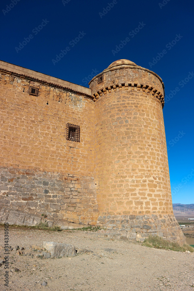 Towers of medieval spanish castle La Calahorra on the hill against azure winter sky