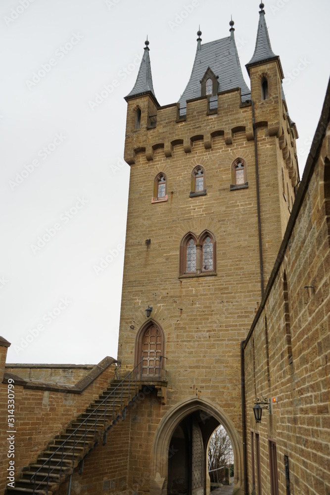 a tower of a castle with a  underpass and stairway. the tower is connected with a fortification wall. Hohenzollern castle. Bisingen Germany.