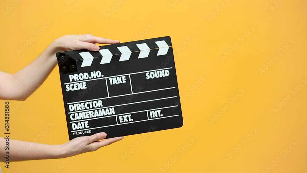 Close up female hold in hand classic director clear empty black film making clapperboard isolated on yellow orange background studio. Cinematography production concept. Copy space advertising mock up.