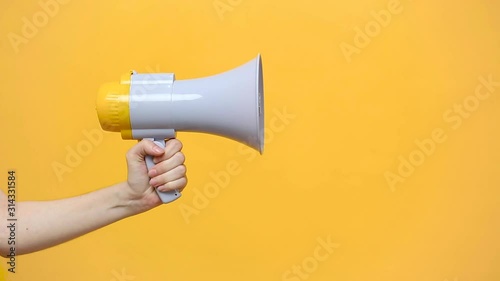 Close up female hold in hand bullhorn public address megaphone isolated on yellow background. Hot news, announce discounts sale, hurry up, communication concept. Copy space. Advertising area, mock up. photo