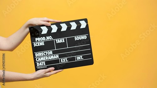 Close up female hold in hand classic director clear empty black film making clapperboard isolated on yellow orange background studio. Cinematography production concept. Copy space advertising mock up. photo