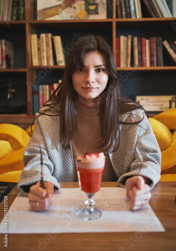 young woman in cafe with cocktail holding a cutlery