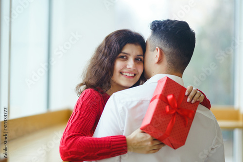 Wallpaper Mural Happy couple with gift hugging. Red gift box in the hands of a couple in love. Valentine's Day, holiday and surprise concept. Lovers give each other presents. Relationship and love concept. Torontodigital.ca