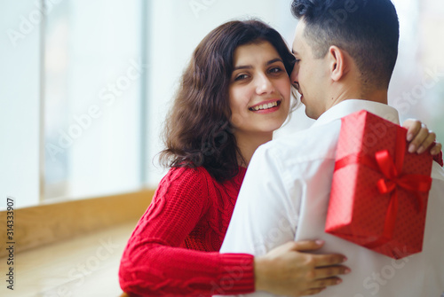 Wallpaper Mural Happy couple with gift hugging. Red gift box in the hands of a couple in love. Valentine's Day, holiday and surprise concept. Lovers give each other presents. Relationship and love concept. Torontodigital.ca