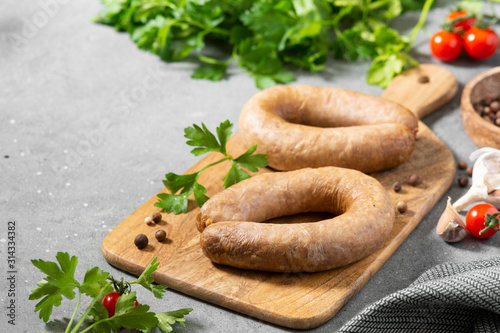 Sausage with spices and parsley on a wooden Board on a gray kitchen background. With space for text