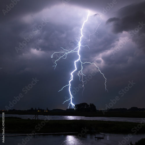 Bright lightning bolt with many side branches strikes down to earth