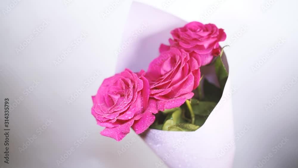 Bouquet of flowers from pink roses with drops of water on gray background. Three big and fluffy roses in wrapping paper. Bouquet of flowers from pink roses with drops of water on gray background. Three big and fluffy roses in wrapping paper.