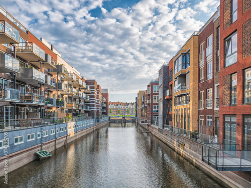 Colorful apartments on the both sides of canal in Amsterdam with boats and blue sky
