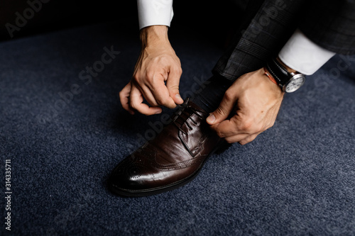 Strong man's hands are tying laces on the classic shoes