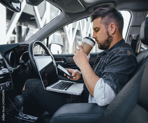 Young handsome driver man with laptop serfing internet and drink black coffee © klepach