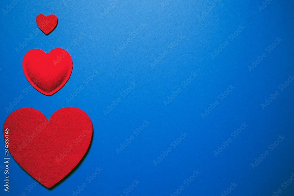 Decorative felt hearts on blue background. Abstract backdrop with copy space. Love and romance theme.