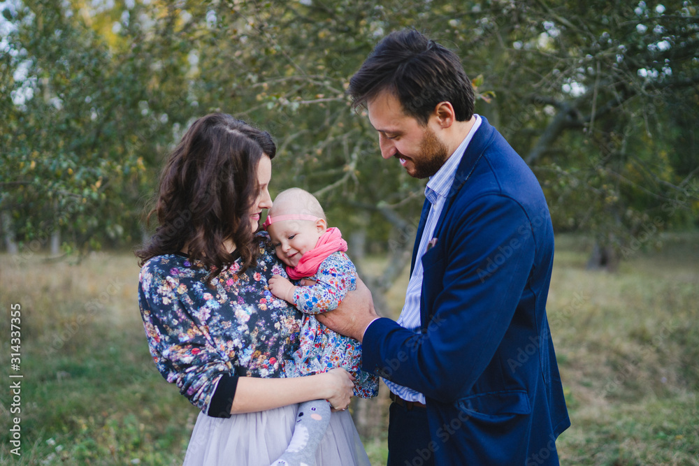 Young happy caucasian couple with little baby girl. Parents and daughter walking and having fun together. Mother and father play with child outdoors. Family, parenthood, childhood, happiness concept. Young happy caucasian couple with little baby girl. Parents and daughter walking and having fun together. Mother and father play with child outdoors. Family, parenthood, childhood, happiness concept.