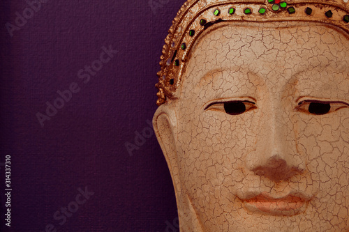 Closeup of buddha face image on dark violet background photo