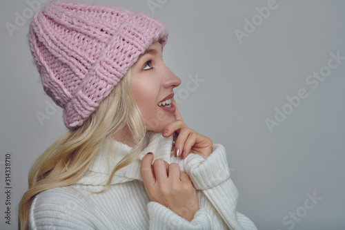 Canvastavla Pretty young blond woman in woollen winter outfit cuddling into the warmth of he