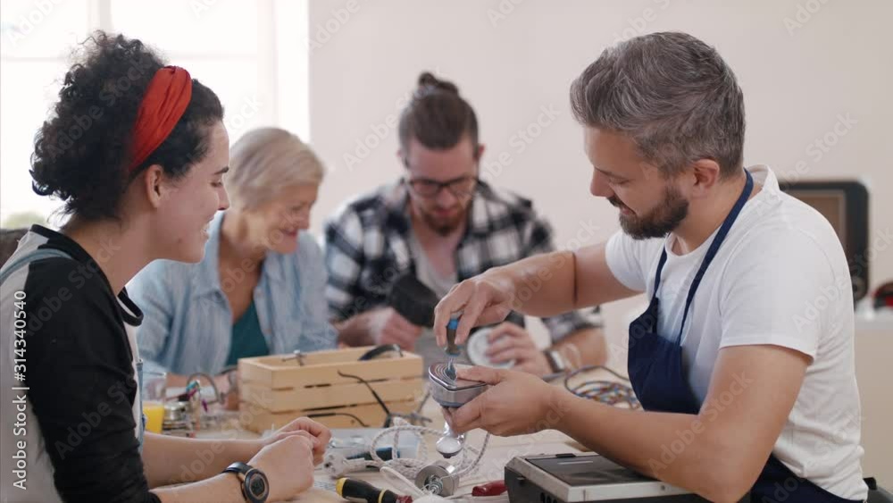 A group of people at repair cafe repairing household electrical devices.