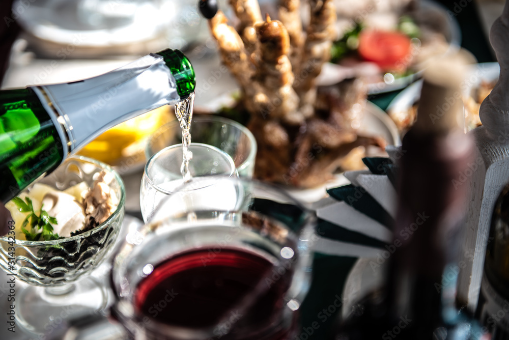champagne is poured into a glass over a festive table with bright sunlight