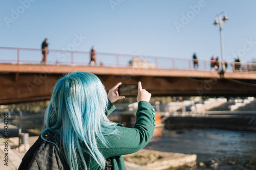 Backside of girl with blue hair making photos