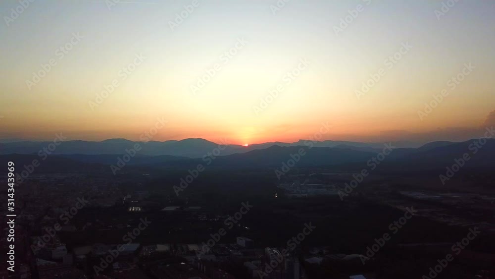 Aerial, rising, drone shot, of sunset above the city of Girona, on a sunny, summer evening, in Catalonia, Spain Aerial, rising, drone shot, of sunset above the city of Girona, on a sunny, summer evening, in Catalonia, Spain