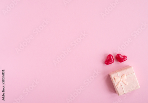 Valentines day flat lay with two red hearts and present box on pink background. Top view, copy space.