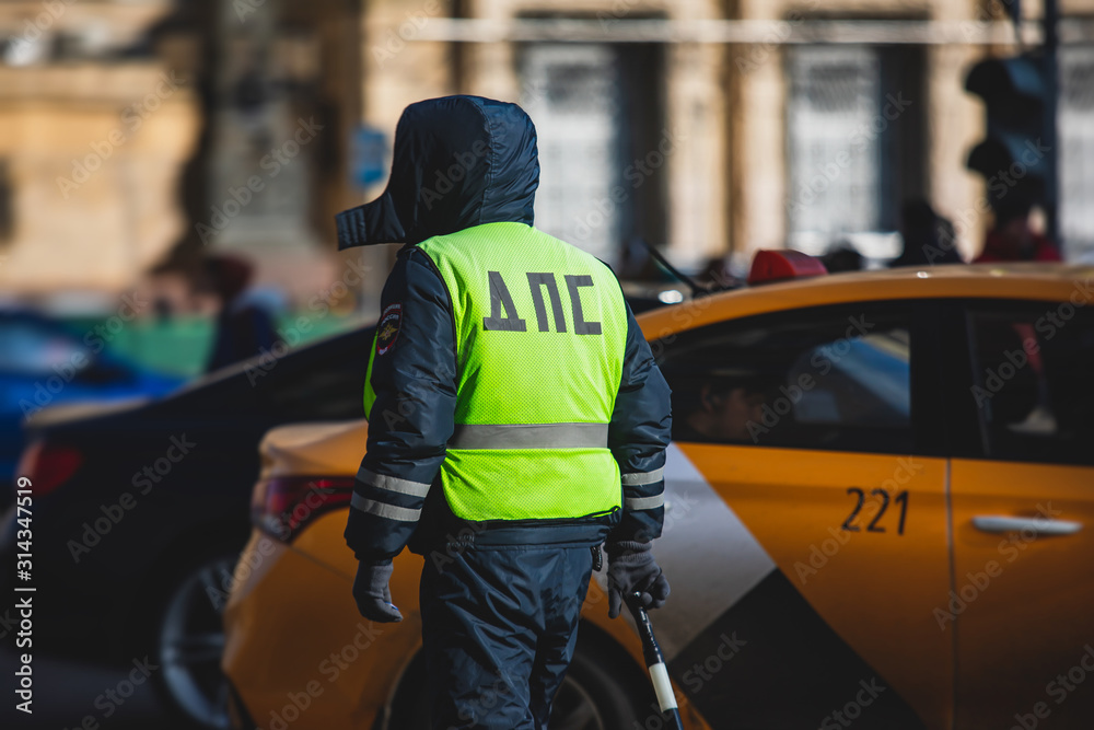 Fototapeta premium Russian Inspector of traffic police highway patrol regulates the movement of transport in the center of Moscow, in yellow vest jacket with a sign 