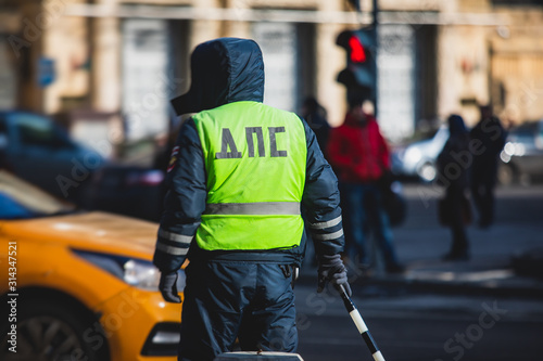 Russian Inspector of traffic police highway patrol regulates the movement of transport in the center of Moscow, in yellow vest jacket with a sign "DPS - Traffic Patrol Police"