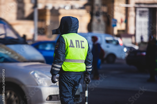 Russian Inspector of traffic police highway patrol regulates the movement of transport in the center of Moscow, in yellow vest jacket with a sign "DPS - Traffic Patrol Police"