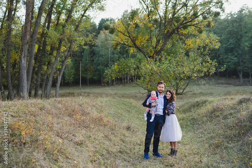 Young happy caucasian couple with little baby girl. Parents and daughter walking and having fun together. Mother and father play with child outdoors. Family, parenthood, childhood, happiness concept.