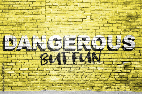 Dangerous but fun lettering saying Graffiti on Brick Wall