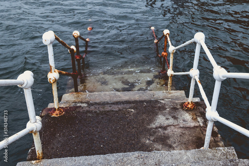 concrete staircase with white metal barriers sinking into the water