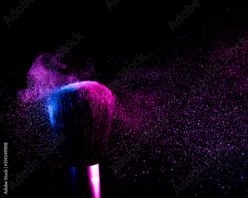 flying shadows from colliding makeup brushes. pink and blue light. black background. 