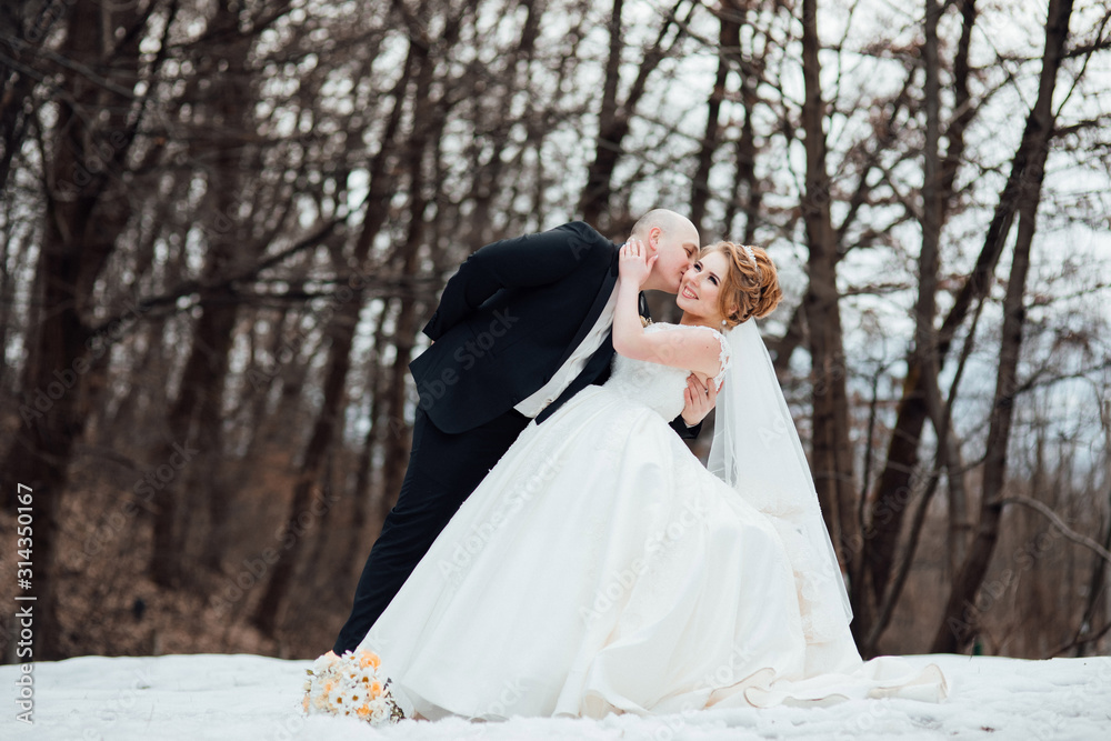 Young bride with groom dancing in the forest. Woman with long white dress and man in black suit with tie. Wedding, engagement rings exchange of young, dress, ring