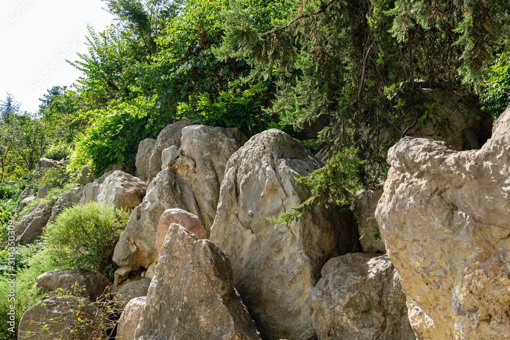Large fragments of rocks, beautiful stones with evergreens as imitation of mountains. Decorative landscape elements in Aivazovsky park in Partenit, Crimea.