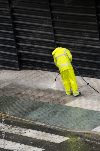 Worker cleaning the sidewalk with pressurized water. Maintenance or cleaning concept