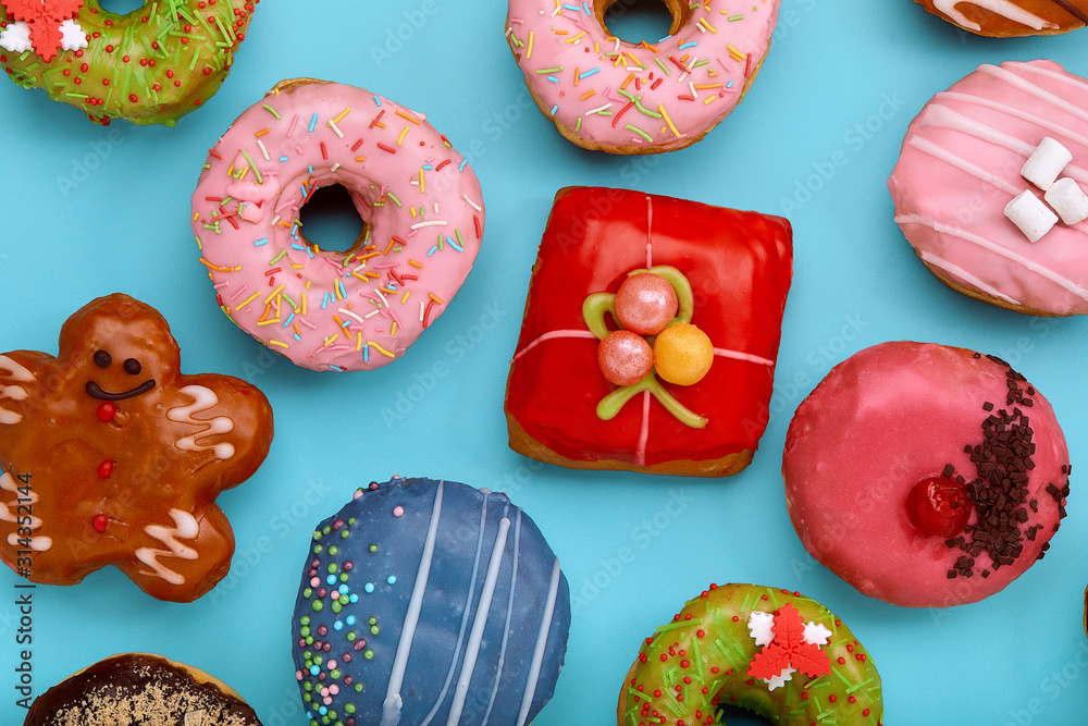 Various colorful donuts on blue background. Top view.