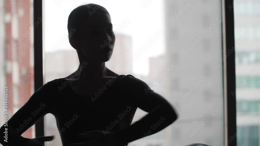 Silhouette. Ballerina in a black tutu dancing ballet in the background of the window and the city. Slow motion. Steadicam shot Close up Silhouette. Ballerina in a black tutu dancing ballet in the background of the window and the city. Slow motion. Steadicam shot Close up