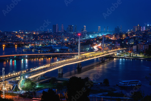 Night view of Istanbul, scenic cityscape with buildings in lights, bridge, bay and blue sky, Turkey. Image taken from popular terrace near the Suleymaniye mosque, outdoor travel background