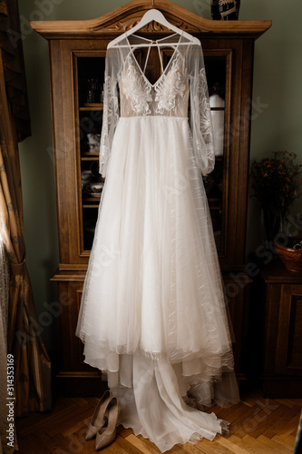Beautiful tender wedding dress is hanging in the room