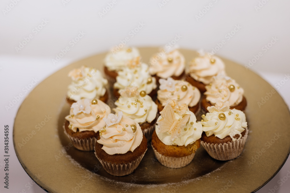 Front view of delicious cupcakes with whipped cream on the golden plate