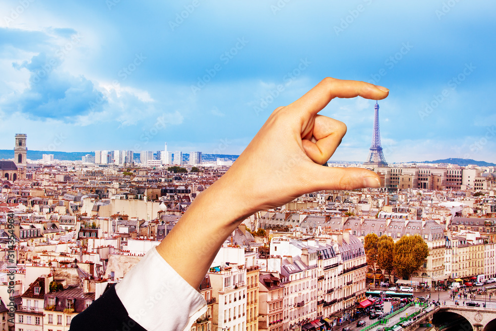 Hand hold between fingers Eifel tower in Paris