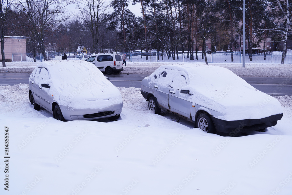Two snow cars stand near the road in the winter city. Two snow cars stand near the road in the winter city.