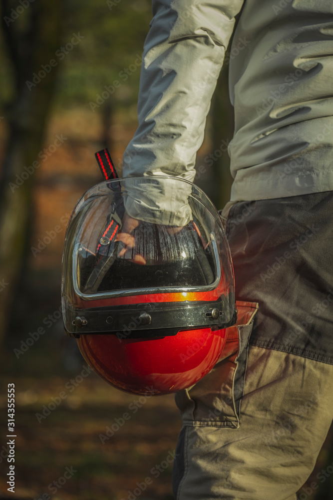 Pessoa a segurar antigo capacete vermelho de mota com viseira transparente  Stock Photo | Adobe Stock