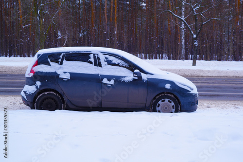 View of the car in the snow near the road in winter.
