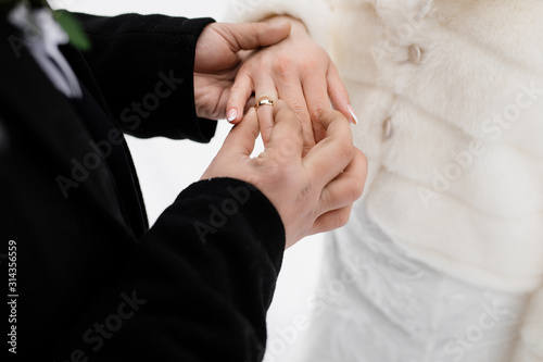 Groom is putting on the wedding ring on his future wife outdoors