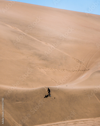 silhouette of man practice sandboarding in the desert of Peru.