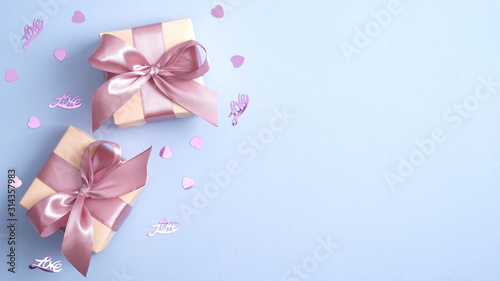 Valentine gift boxes with pink ribbon bow on pastel blue background with heart shaped confetti. Valentines or Mother day banner design. Flat lay, top view, copy space.