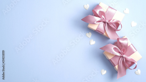 Valentine gift boxes with pink ribbon bow on pastel blue background with heart shaped confetti. Valentines or Mother day banner design. Flat lay  top view  copy space.