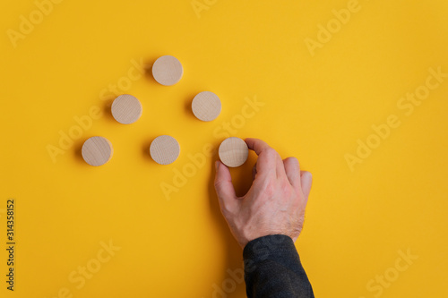 Placing blank wooden cut circles in a pyramid shape photo