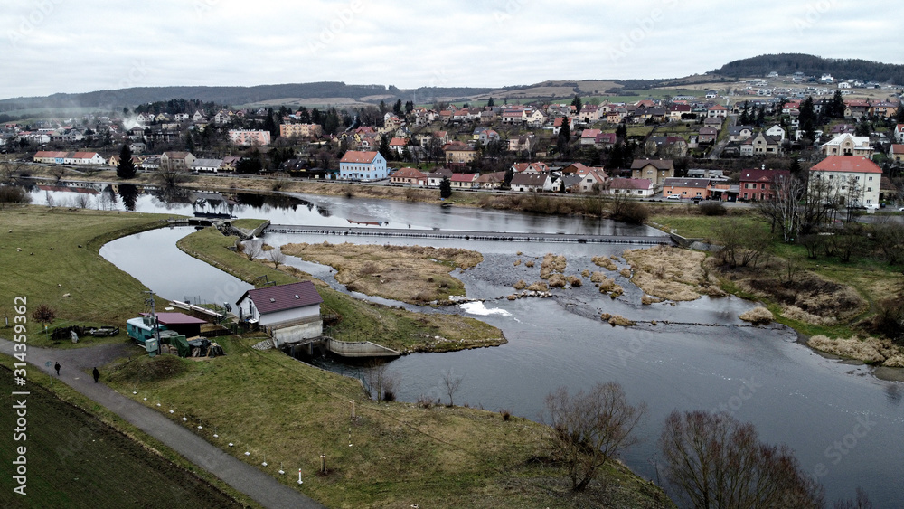 Aerial view of weir in Hyskov village near Beroun. There is a small hydroelectric power station near the weir. Winter without snow in the Czech Republic.