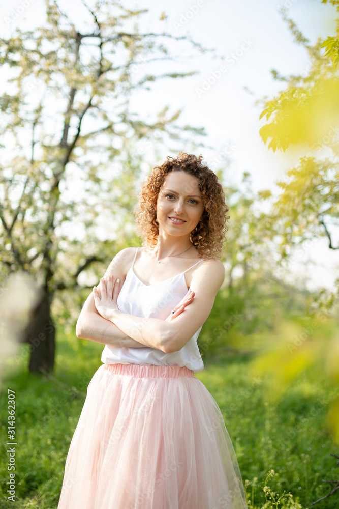 Young attractive girl walks in spring green park enjoying flowering nature. Healthy smiling girl spinning on the spring lawn. Allergy without Young attractive girl walks in spring green park enjoying flowering nature. Healthy smiling girl spinning on the spring lawn. Allergy without