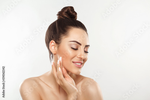 Beauty and Spa Concept. Beautiful Young Woman with Clean Fresh Skin touch face. Facial treatment. Girl Female With Natural Makeup.Cosmetology. Skin Care